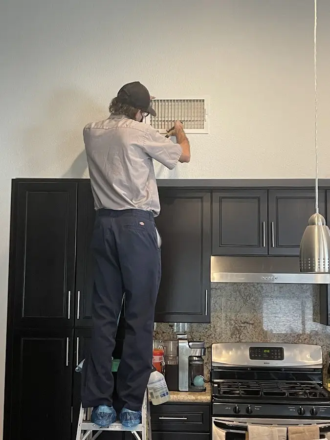 Technician inspecting an air vent during HVAC service in New Whiteland